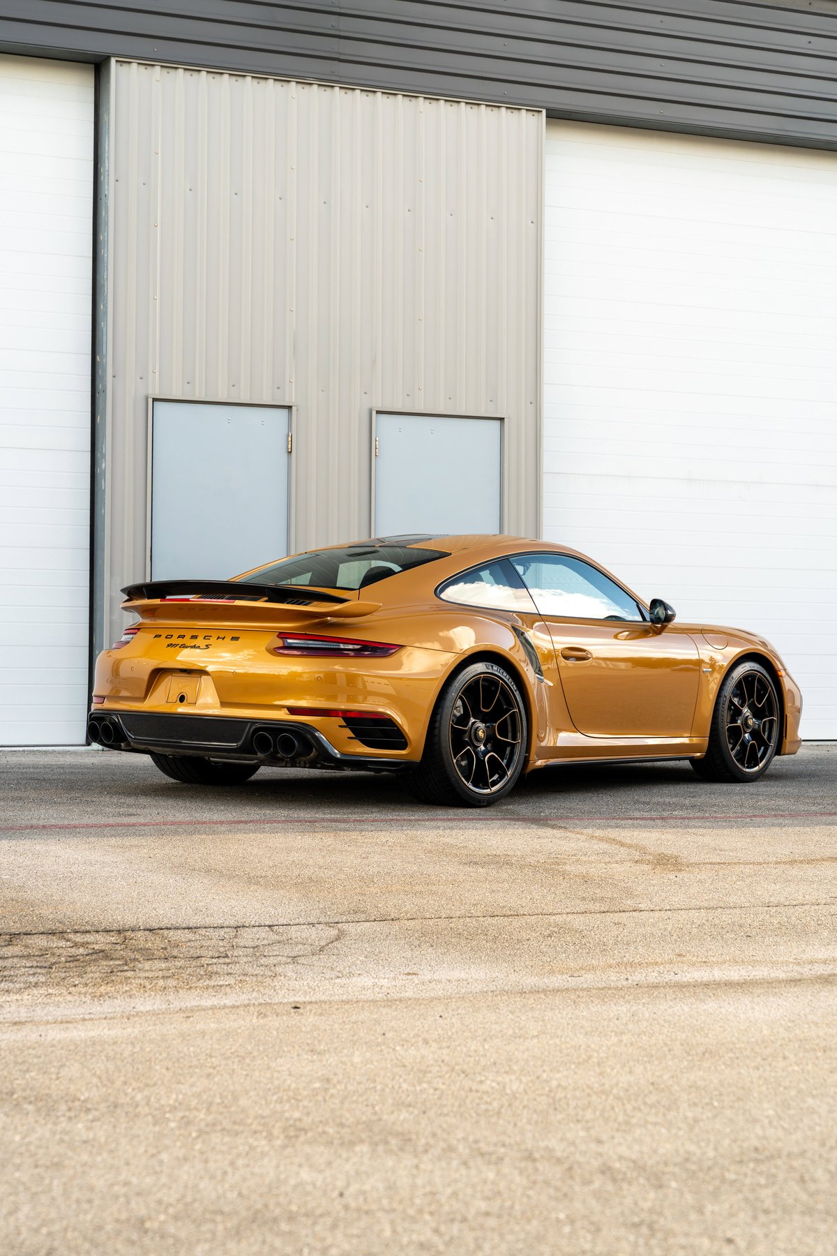 Golden 2018 Porsche 911 Turbo S Exclusive Series with black wheels and spoiler.