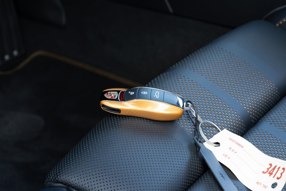 Gold 2018 Porsche 911 Turbo S Exclusive Series key fob with black perforated leather interior.