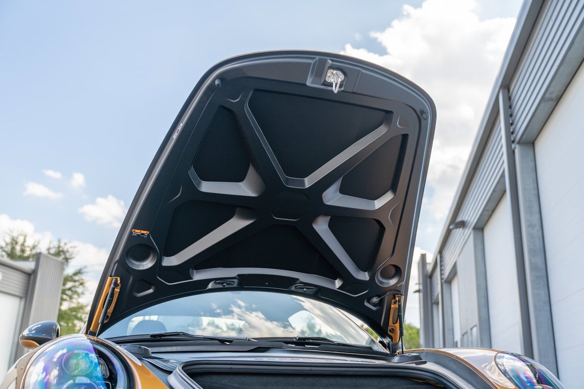 Open hood of a 2018 Porsche 911 Turbo S Exclusive Series in gold with black trim.