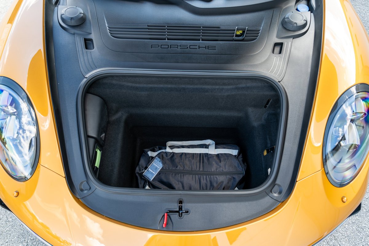 Open front trunk of yellow 2018 Porsche 911 Turbo S Exclusive Series with a black bag inside.