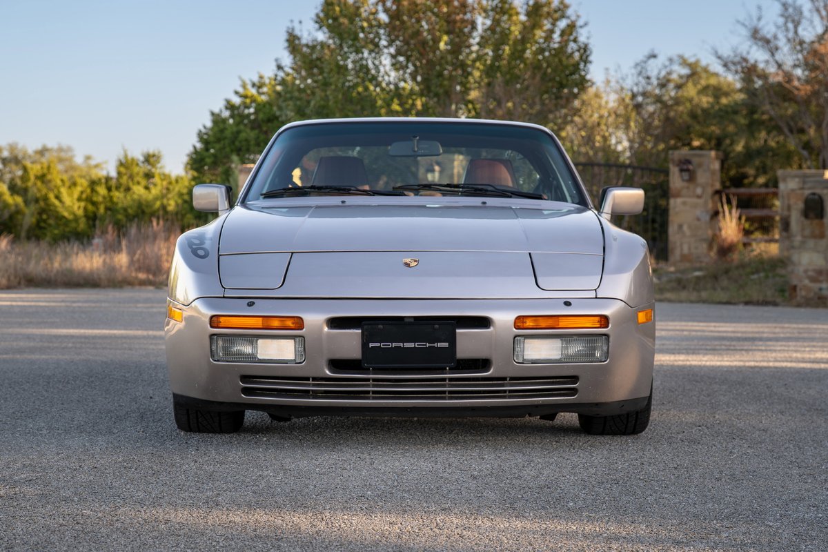 Front view of a silver 1987 Porsche 944 Turbo S, showing pop-up headlights and grille.