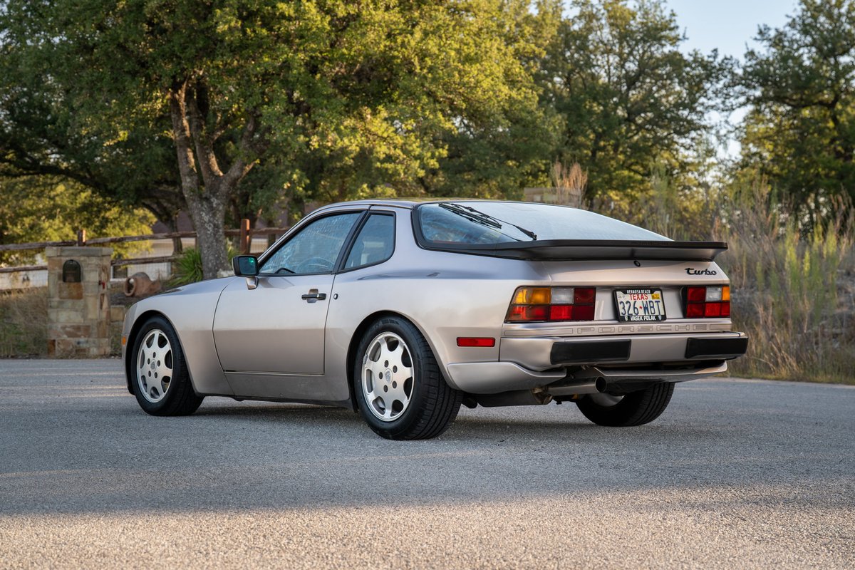 Rear view of a silver 1987 Porsche 944 Turbo S coupe with Fuchs rims and a black rear spoiler.