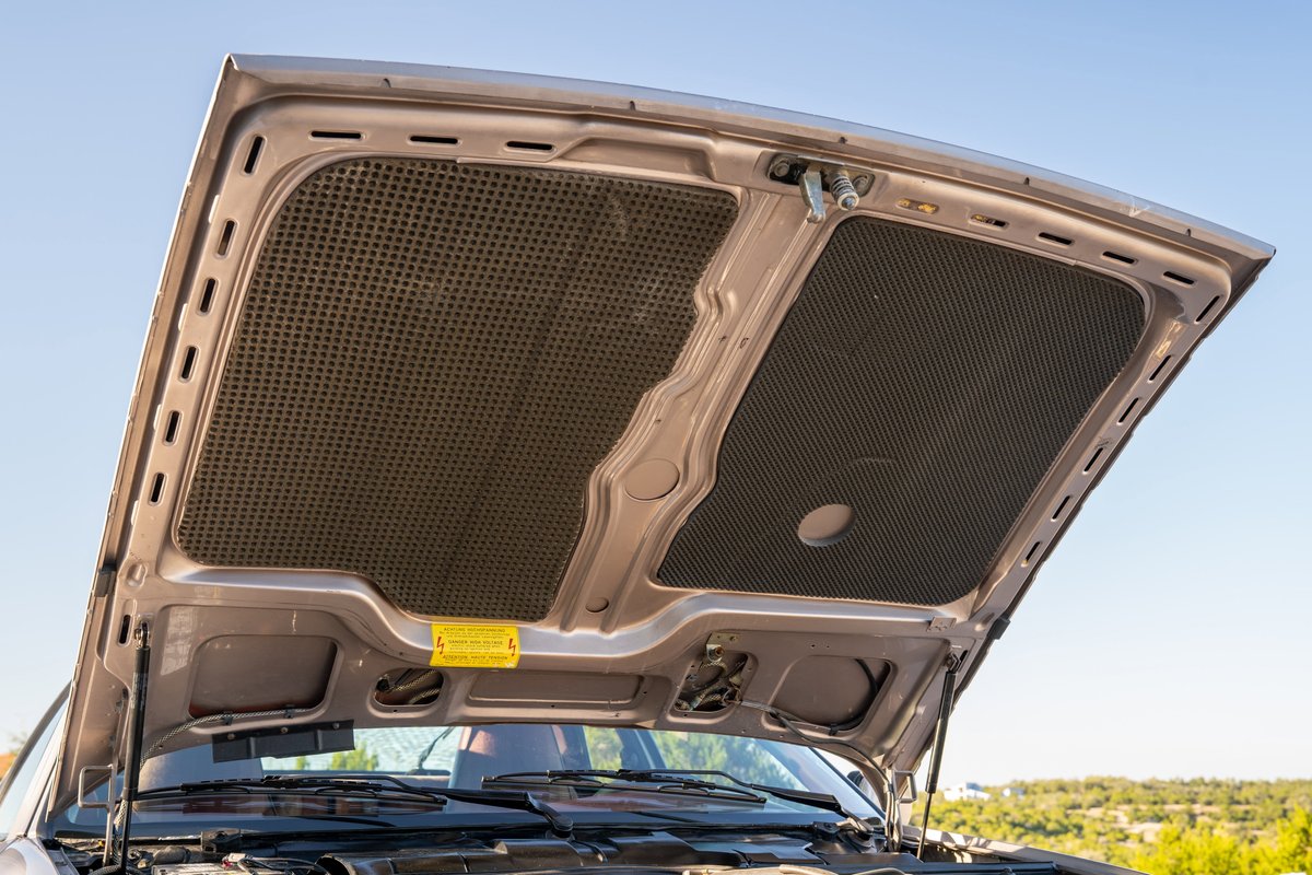 Under the hood of a silver 1987 Porsche 944 Turbo S, showing sound-deadening material.