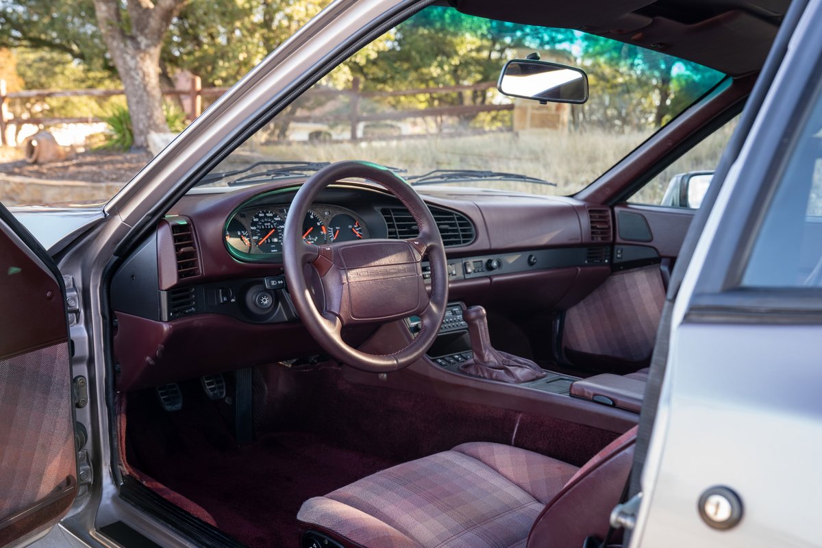 Silver 1987 Porsche 944 Turbo S interior with burgundy dash, plaid seats, and manual shifter.