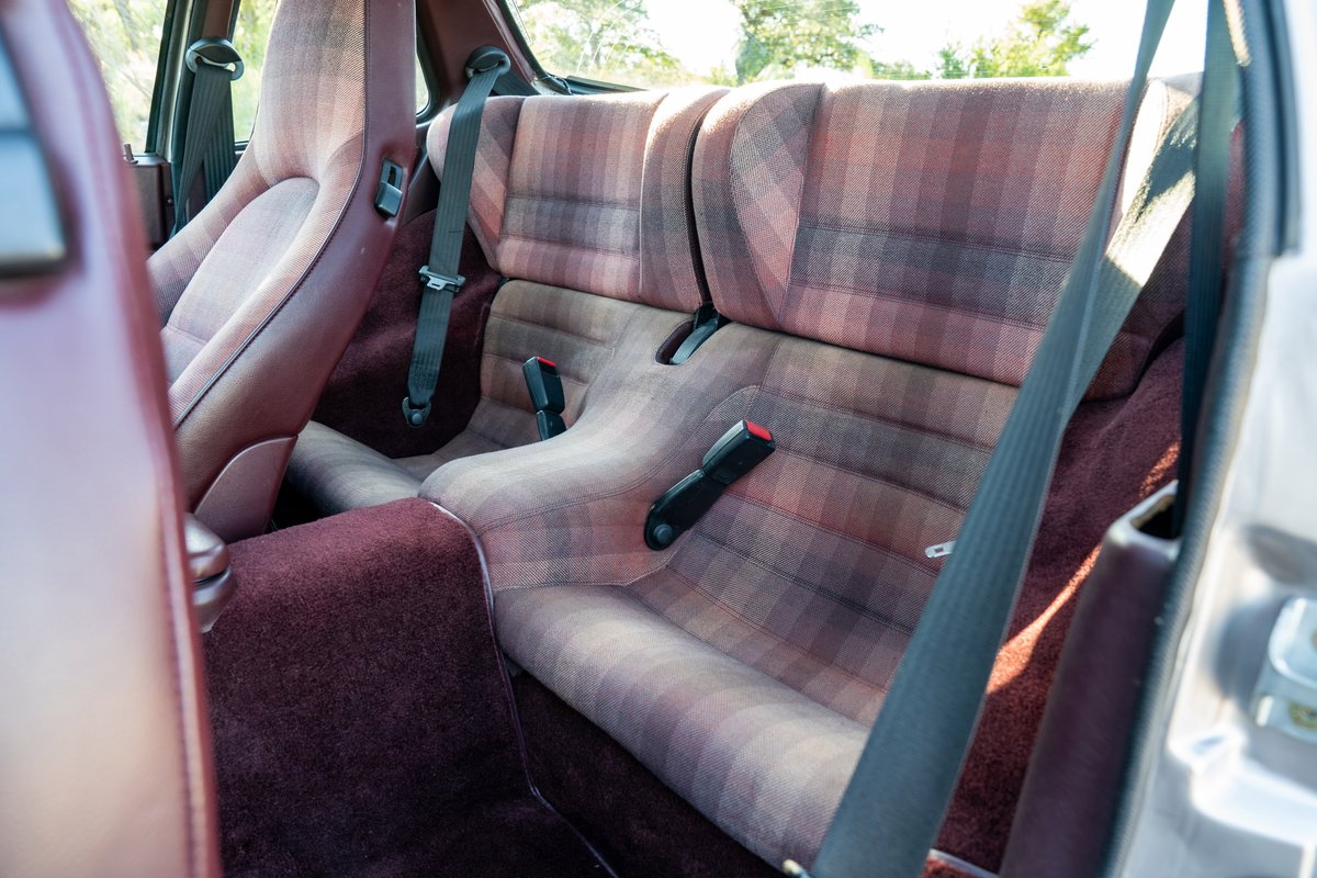 1987 Porsche 944 Turbo S interior with plaid fabric seats and maroon carpeting.
