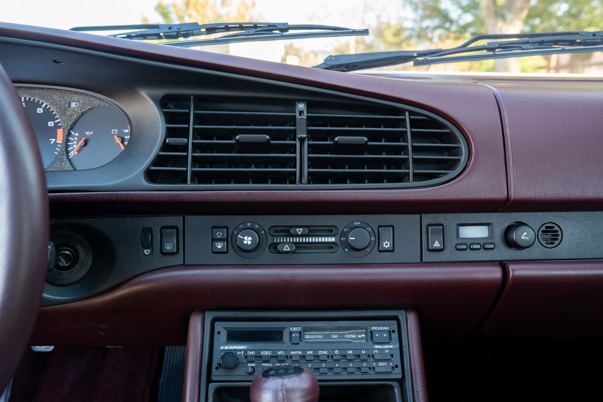 Interior view of a silver 1987 Porsche 944 Turbo S, showing the dashboard with vents and radio.