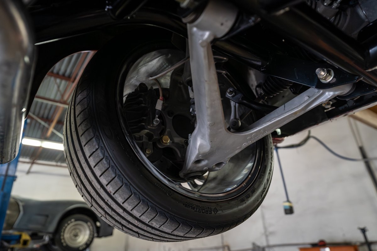 Close-up view of a classic 1965 Chevrolet Corvette's suspension and tire.