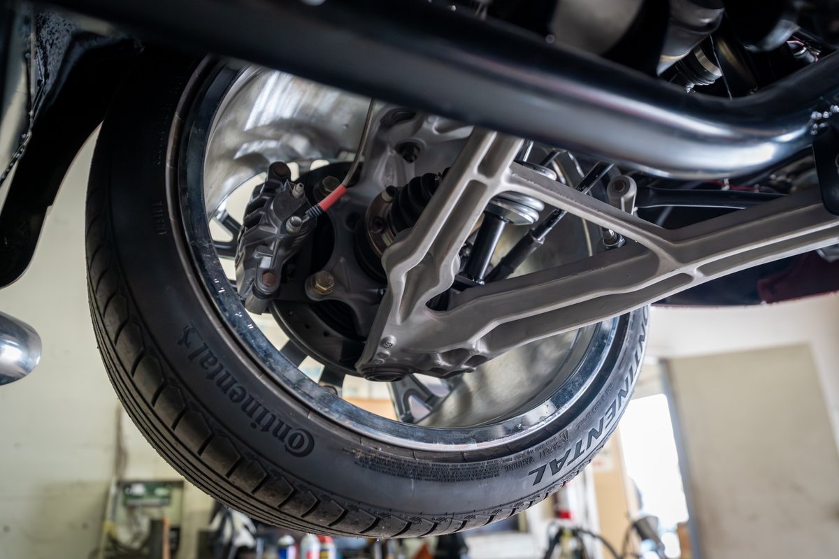 Close-up of a 1965 Chevrolet Corvette's suspension, showing the wheel, brake caliper, and control arm.
