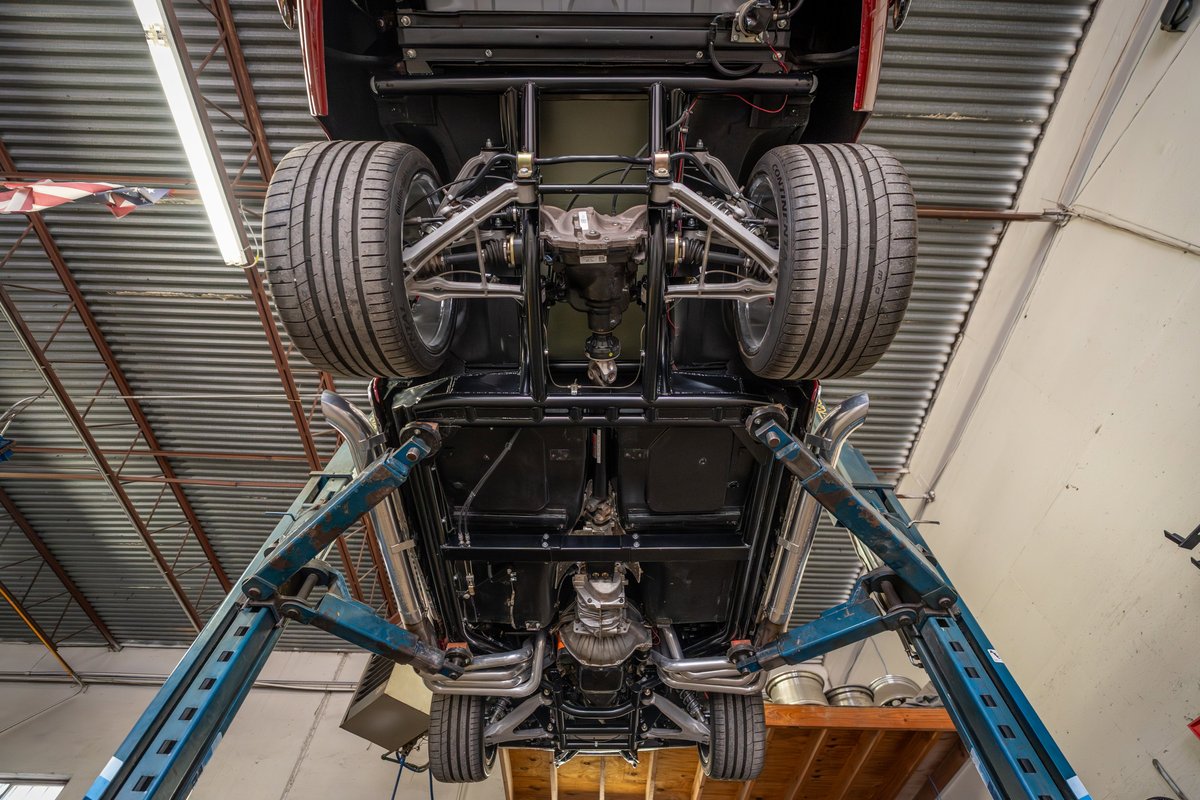 Underside view of a 1965 Chevrolet Corvette hot rod, showing custom exhaust and suspension.