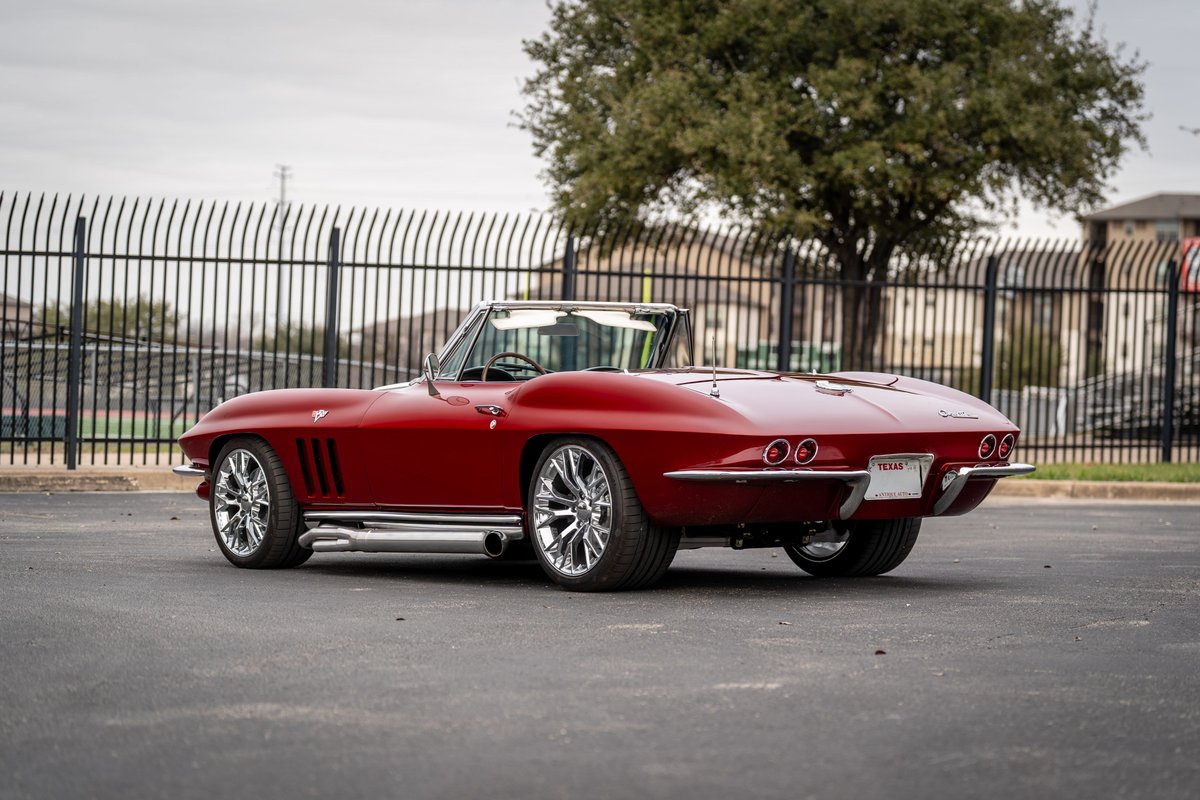 1965 red Chevrolet Corvette Sting Ray convertible with chrome rims and side pipes.