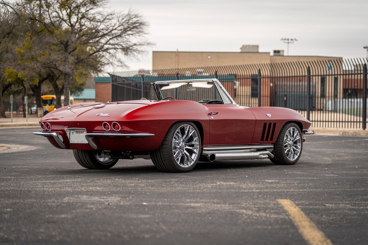 Red 1965 Chevrolet Corvette convertible with custom chrome rims and side exhaust.