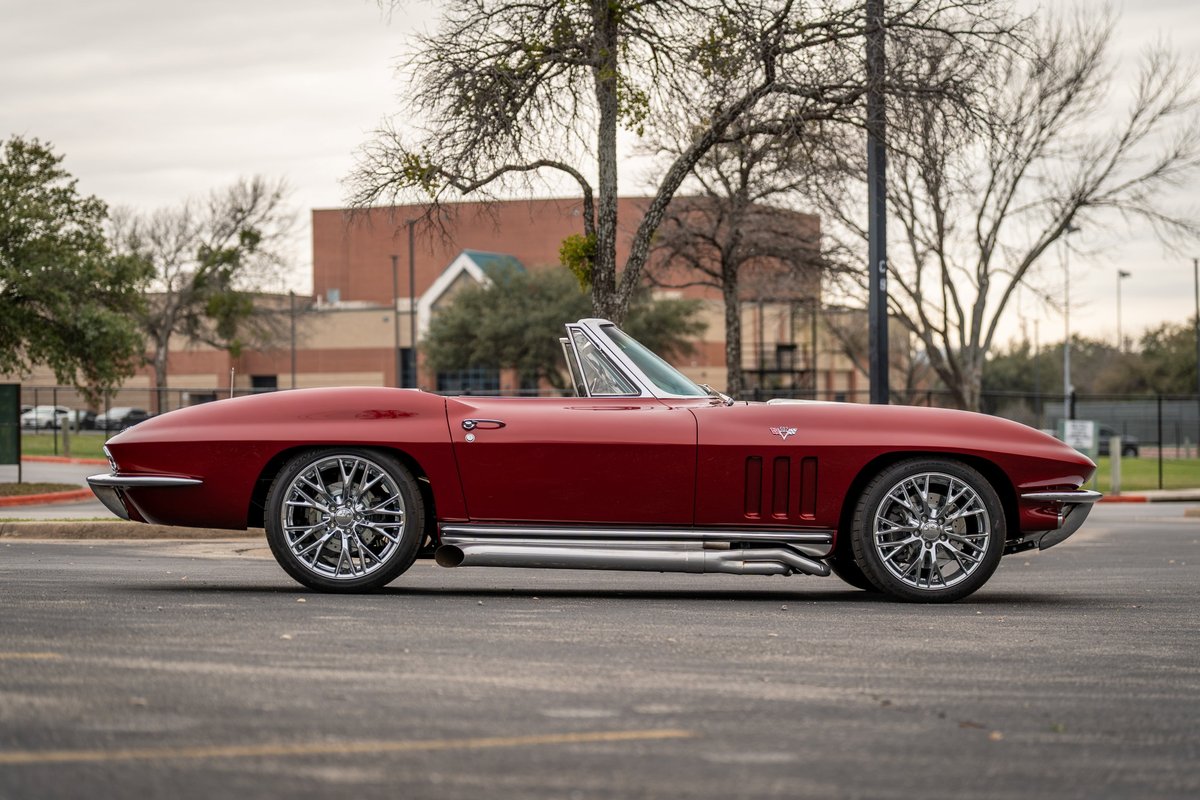 1965 Chevrolet Corvette convertible in red, featuring chrome side pipes and custom multi-spoke rims.