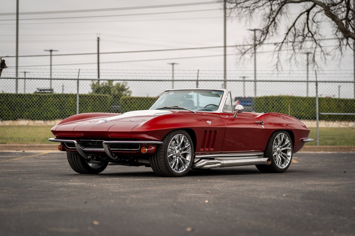 Red 1965 Chevrolet Corvette convertible with chrome rims and side exhaust pipes.