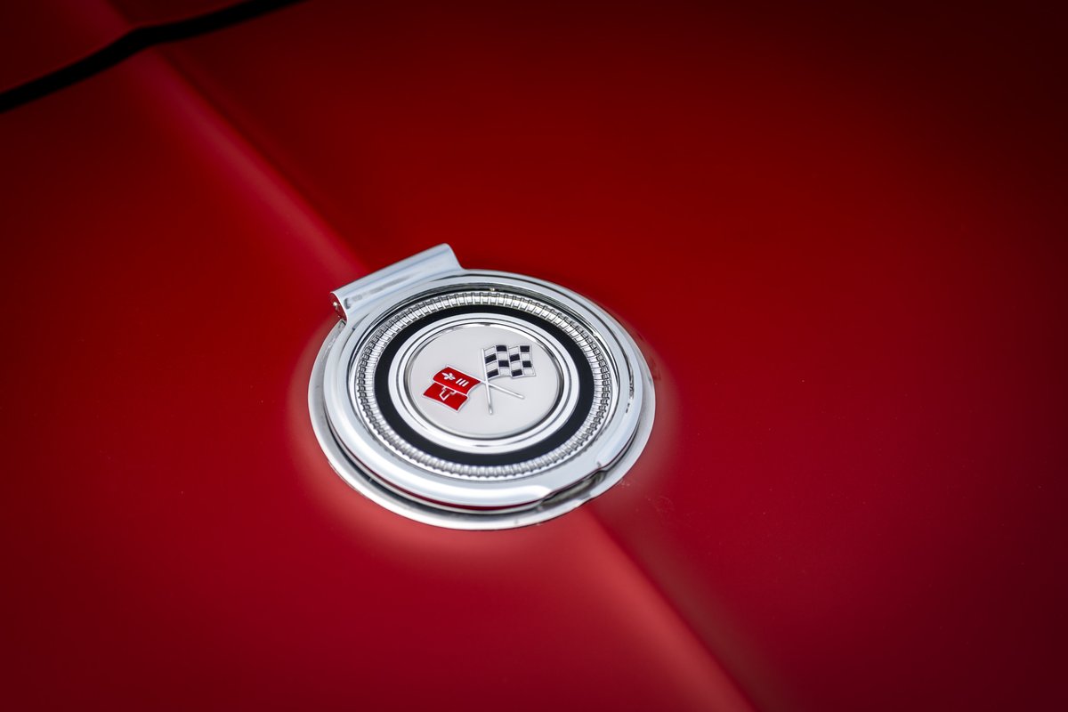 Close-up of a red 1965 Corvette gas cap emblem with checkered flags.