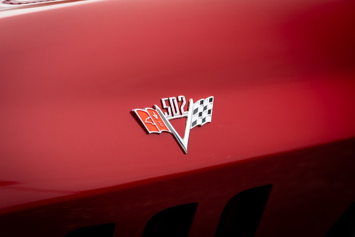 Red 1965 Corvette "502" emblem on shiny red paint.