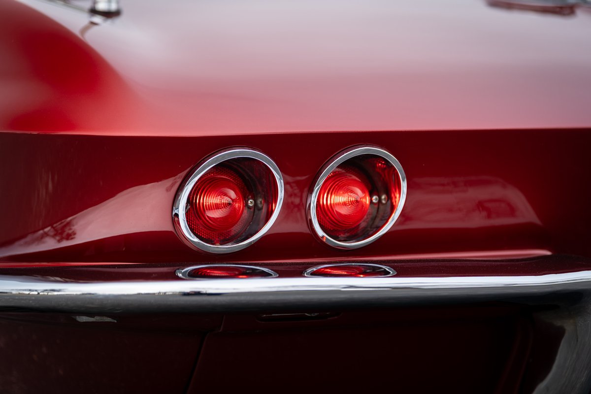 Close-up of red 1965 Corvette's chrome-bezeled round taillights.