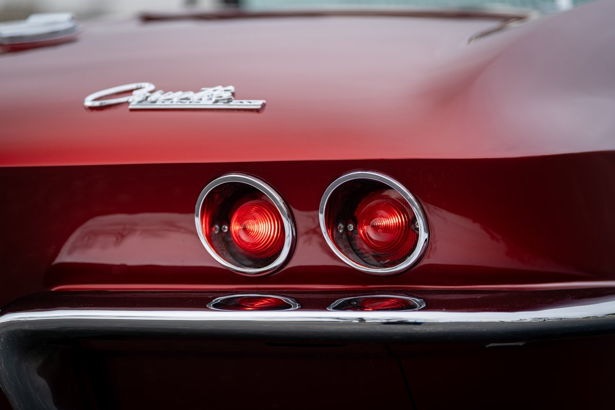 Close-up of the dual round taillights and "Corvette" script on a red 1965 Chevrolet Corvette.
