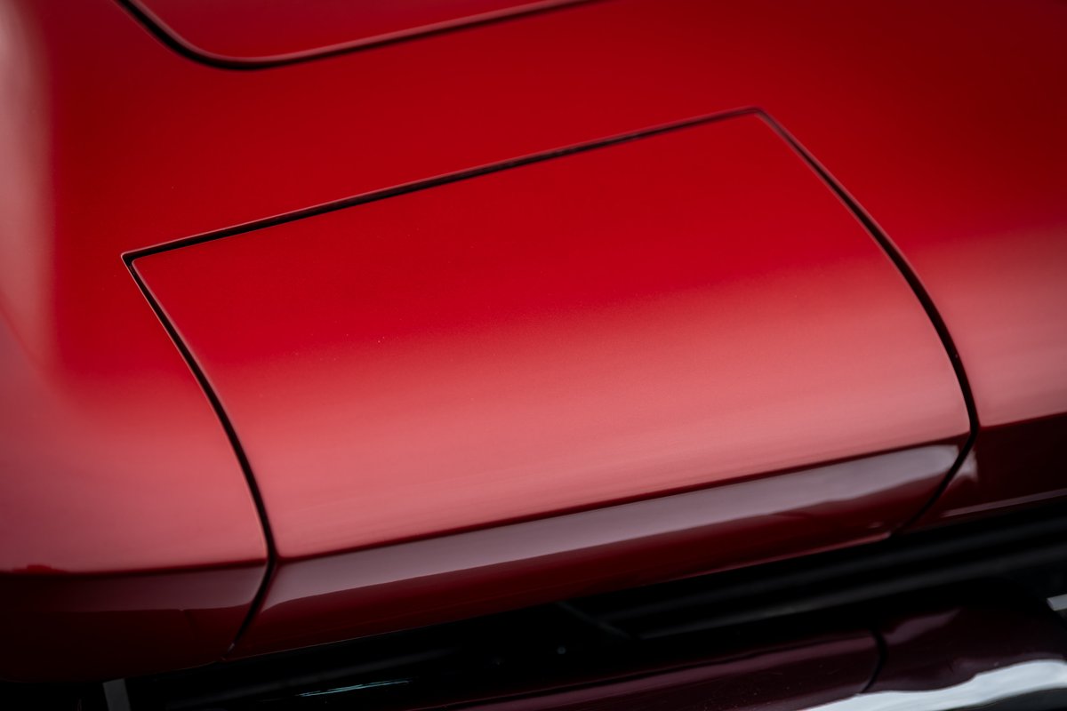 Red 1965 Chevrolet Corvette C2 pop-up headlight cover detail.