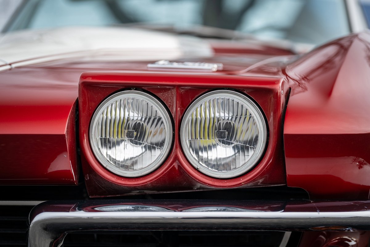 Red 1965 Chevrolet Corvette with twin headlights and chrome bumper.