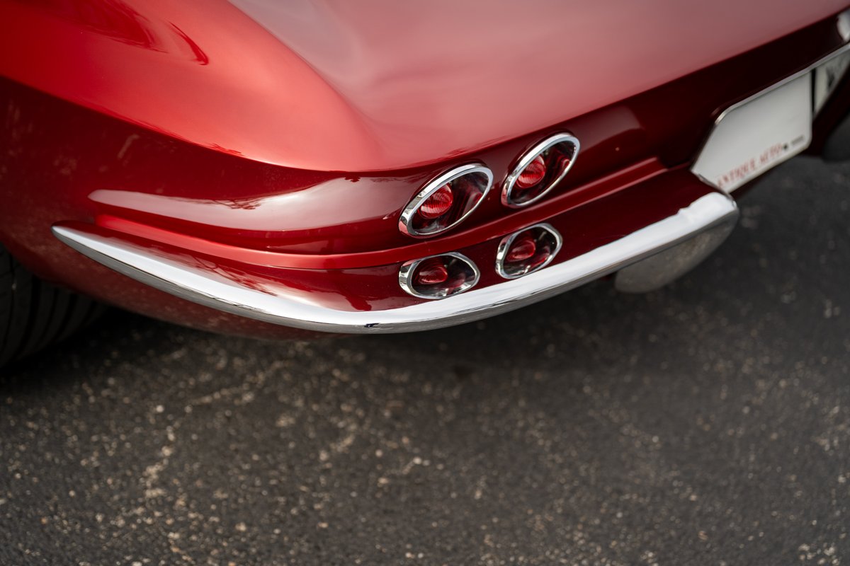 Close-up of a 1965 red Chevrolet Corvette rear with quad taillights and chrome trim.