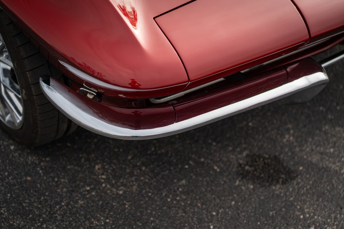 1965 Corvette Stingray, cherry red. Chrome bumper and trim highlight the iconic front end.