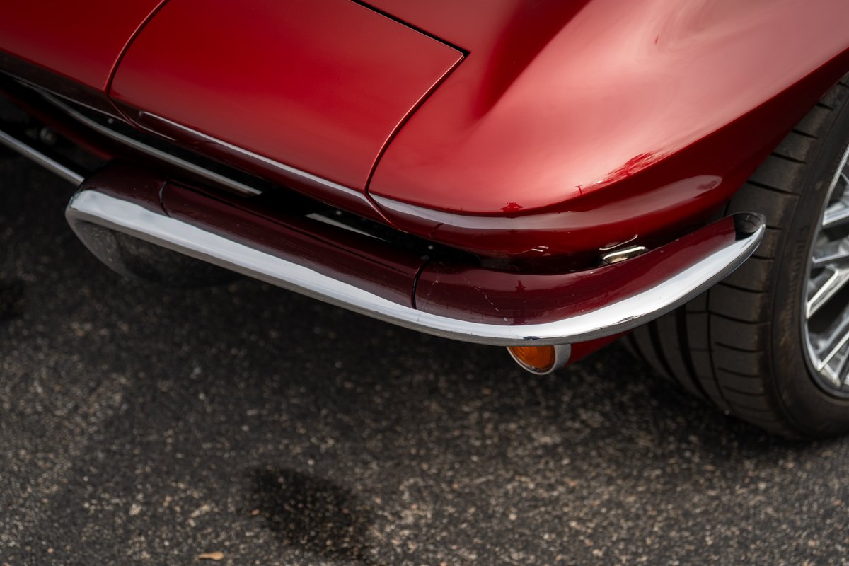 Red 1965 Corvette Sting Ray rear chrome bumper, side exhaust and chrome rim detail.