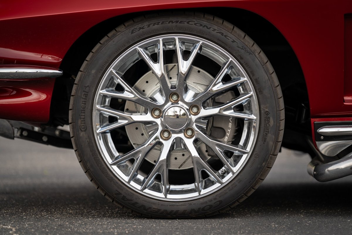 Custom chrome rims and drilled rotors on a red 1965 Chevrolet Corvette.