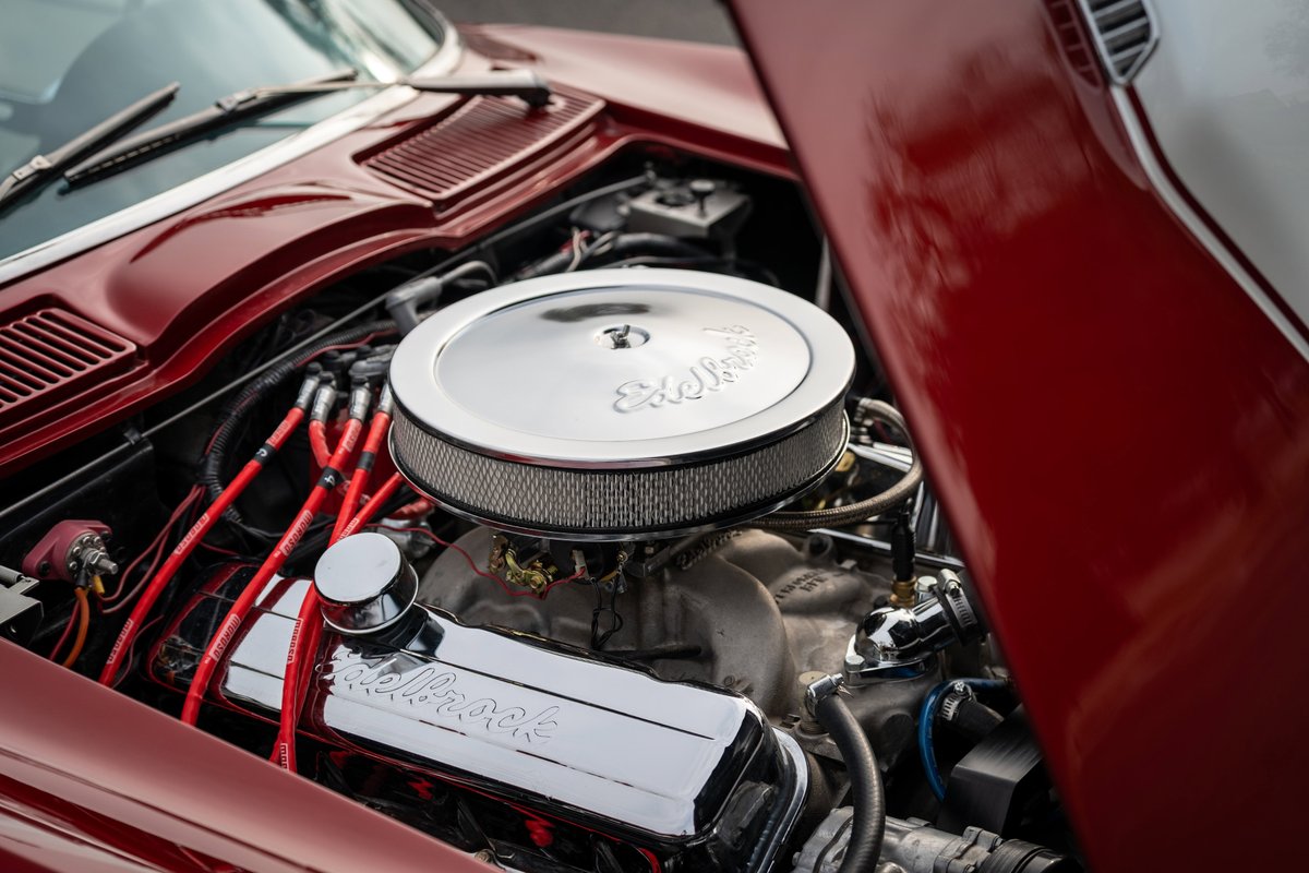 1965 Chevrolet Corvette engine bay: polished Holley valve covers, chrome air cleaner, red spark plug wires.