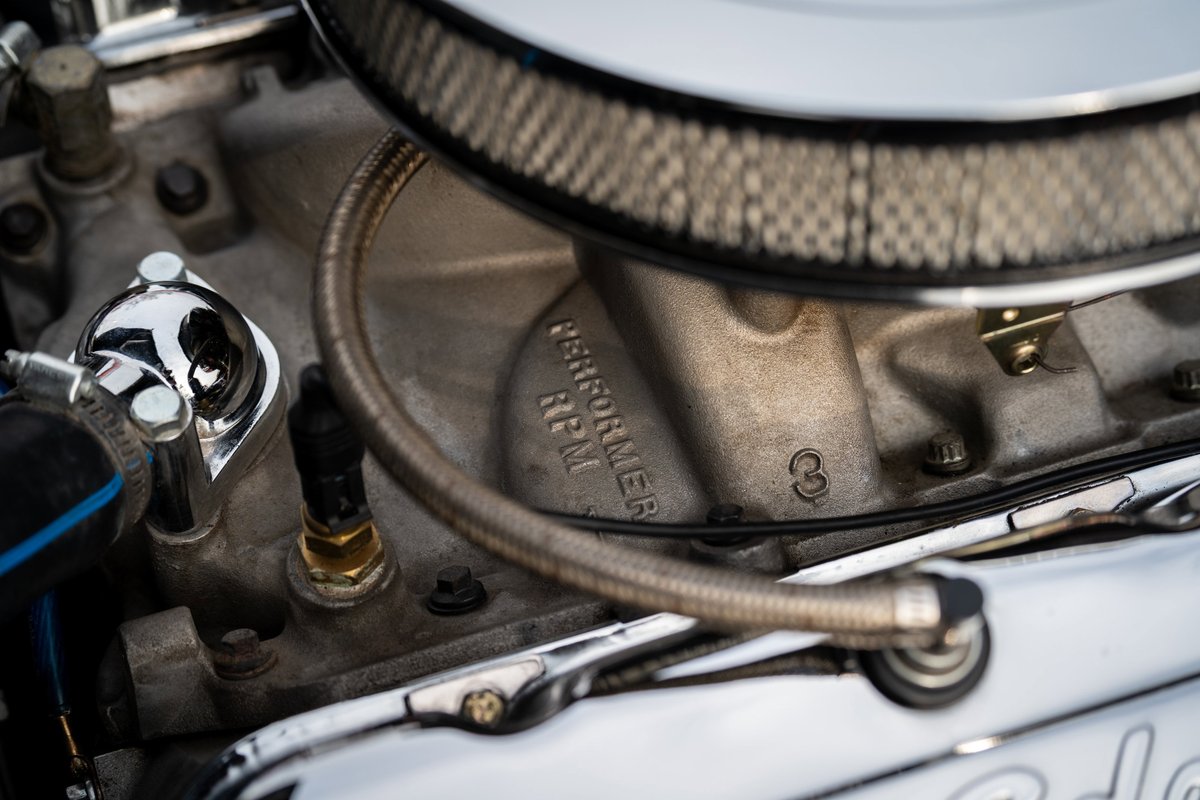 Close-up of a polished chrome thermostat housing on a 1965 Chevrolet Corvette V8 engine manifold.