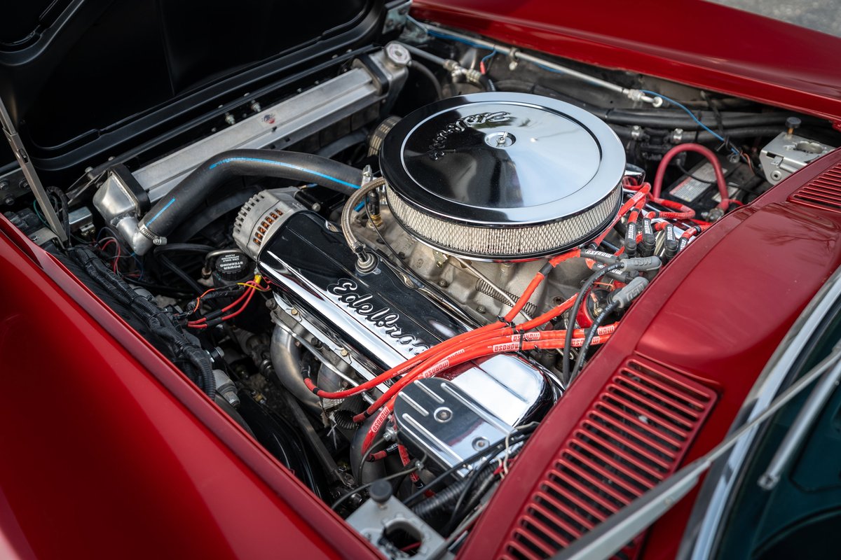 Red 1965 Chevrolet Corvette engine bay with Edelbrock valve covers and chrome air cleaner.
