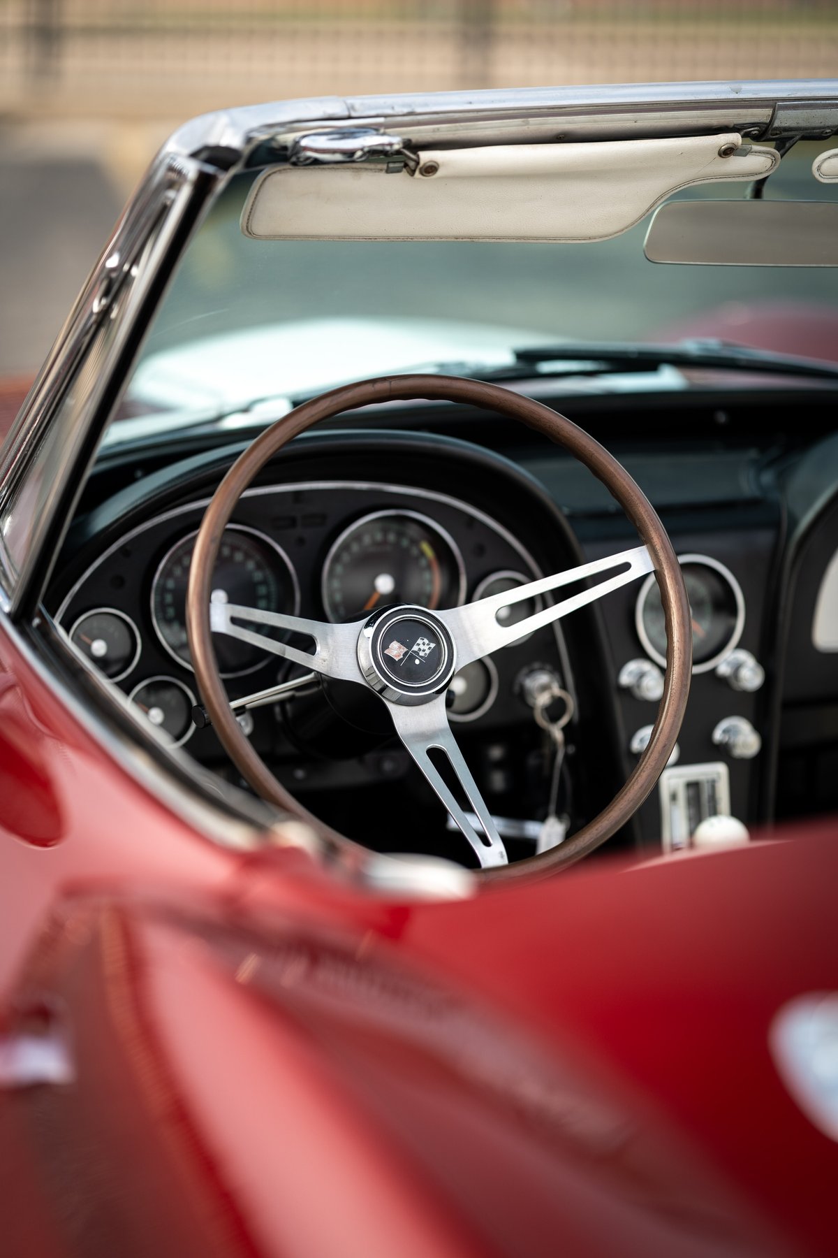 Close up of a 1965 Chevrolet Corvette Sting Ray interior, showing the wood-rimmed steering wheel & dashboard.