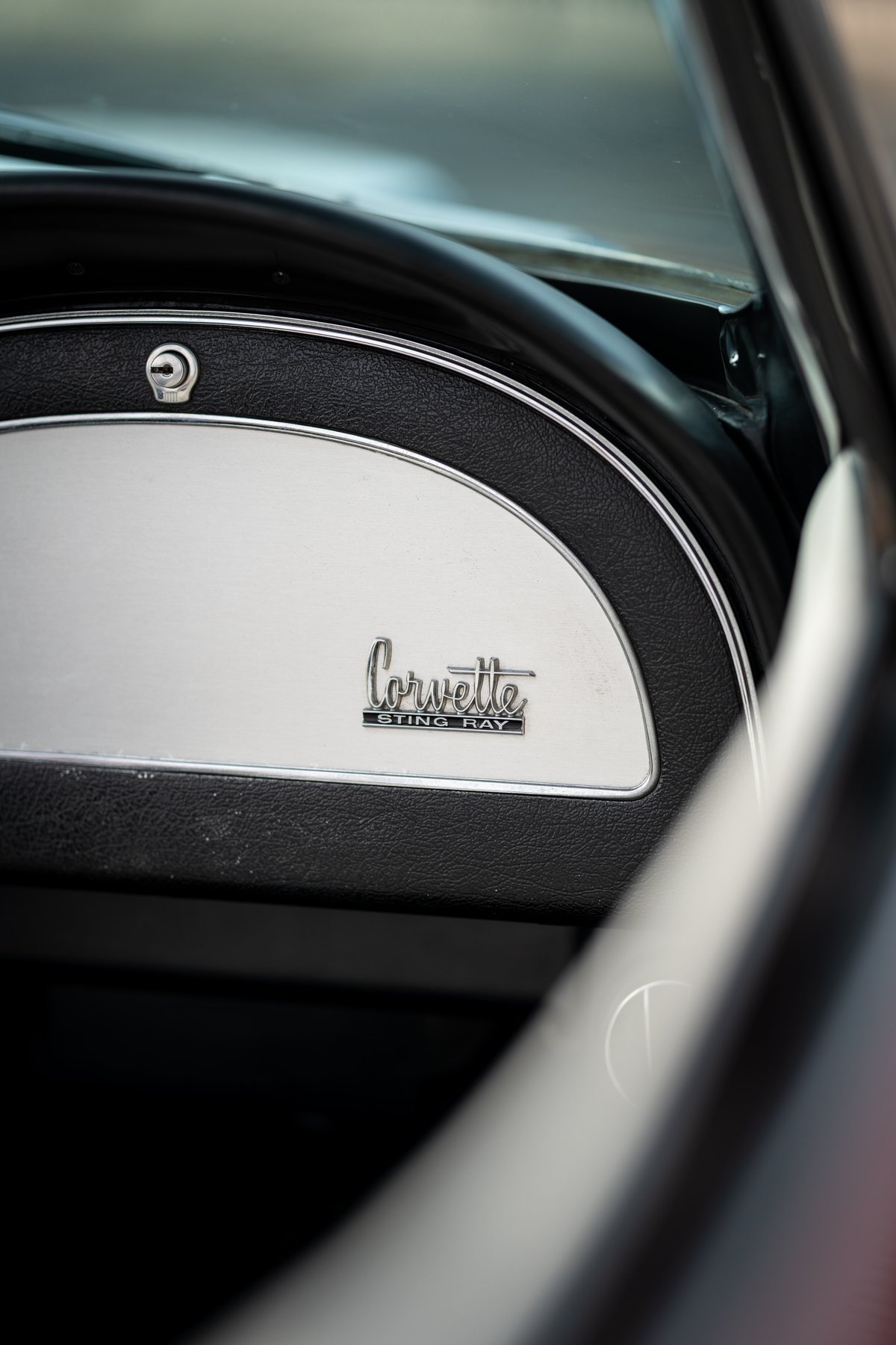 Close-up of the 1965 Chevrolet Corvette Sting Ray dashboard trim and badge.