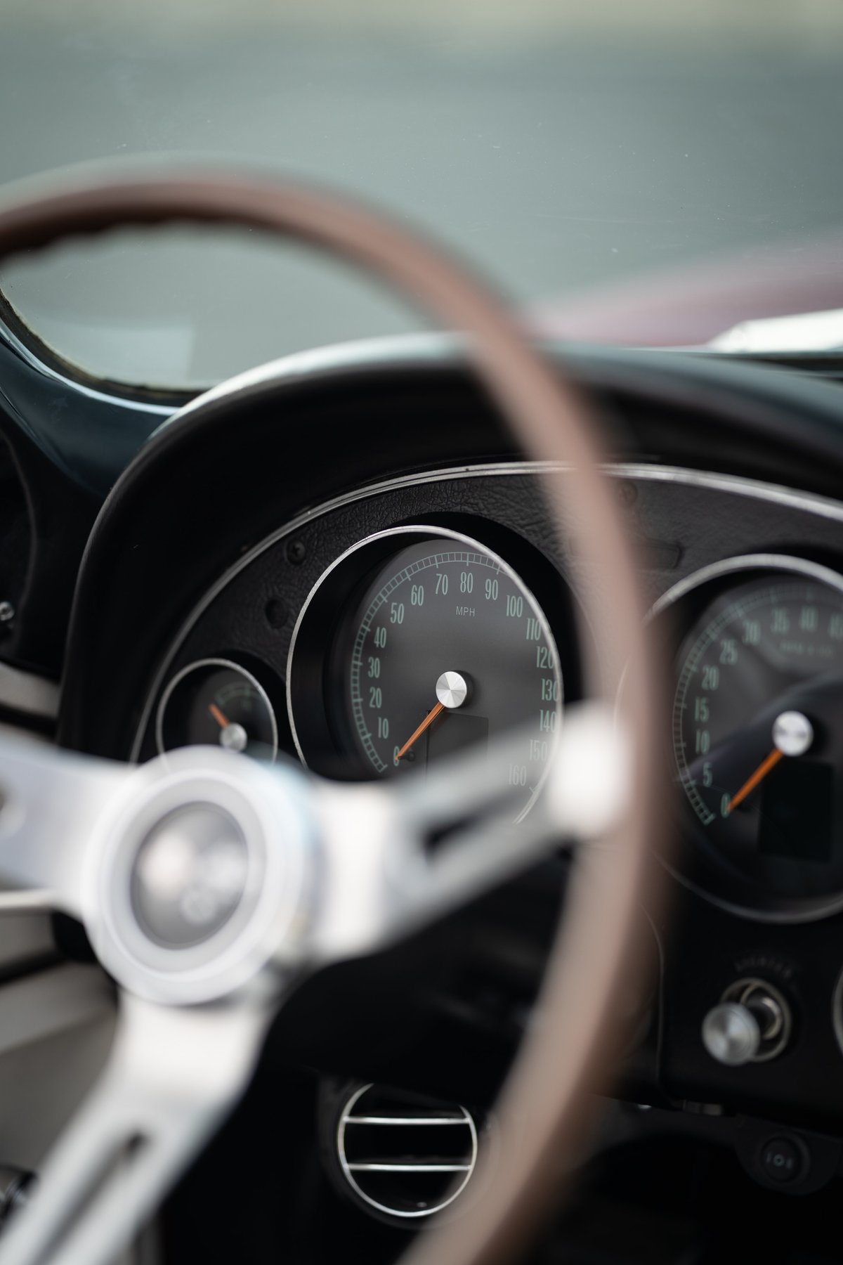 1965 Chevrolet Corvette dashboard with classic gauges and a wood-rimmed steering wheel.