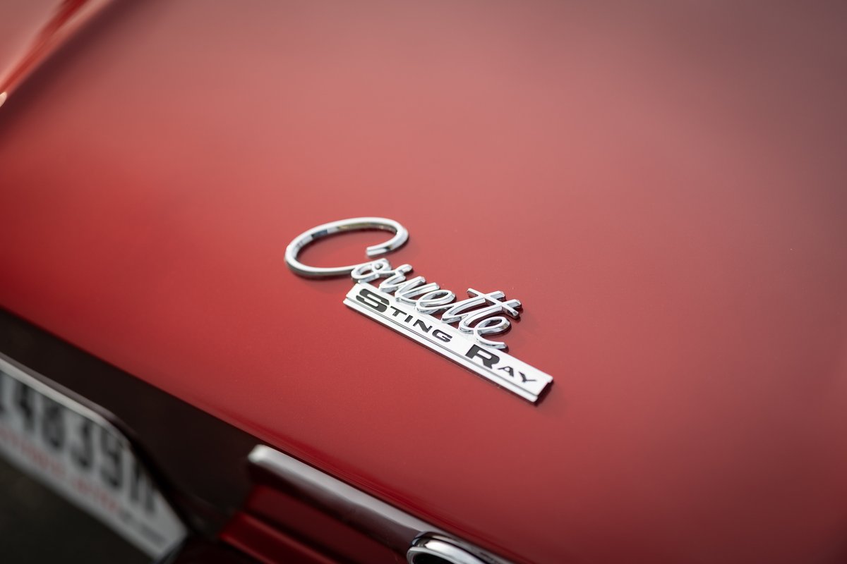 Close-up of a red 1965 Chevrolet Corvette Sting Ray emblem on the hood.