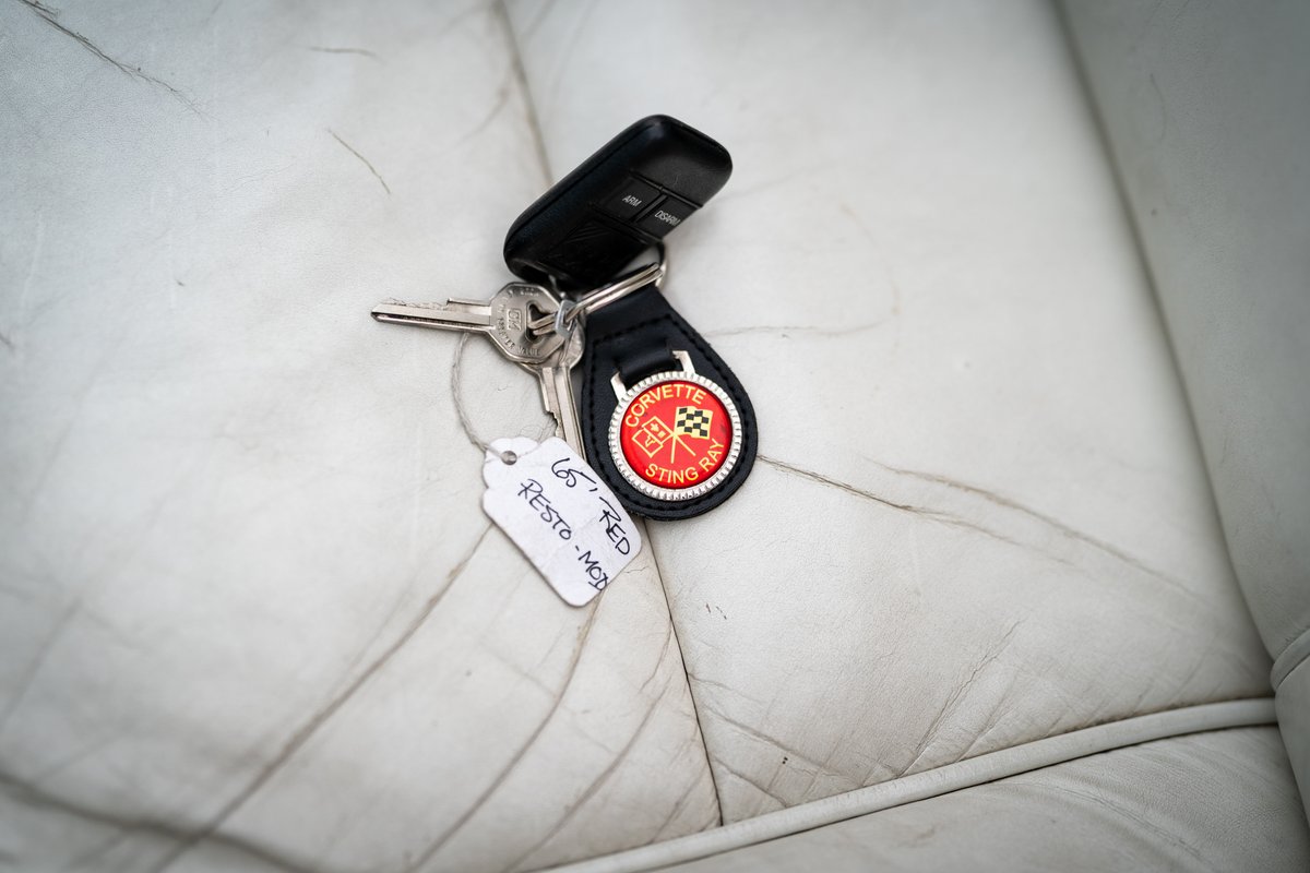 1965 Chevrolet Corvette Sting Ray keys with restoration tag and checkered flag emblem on white leather.