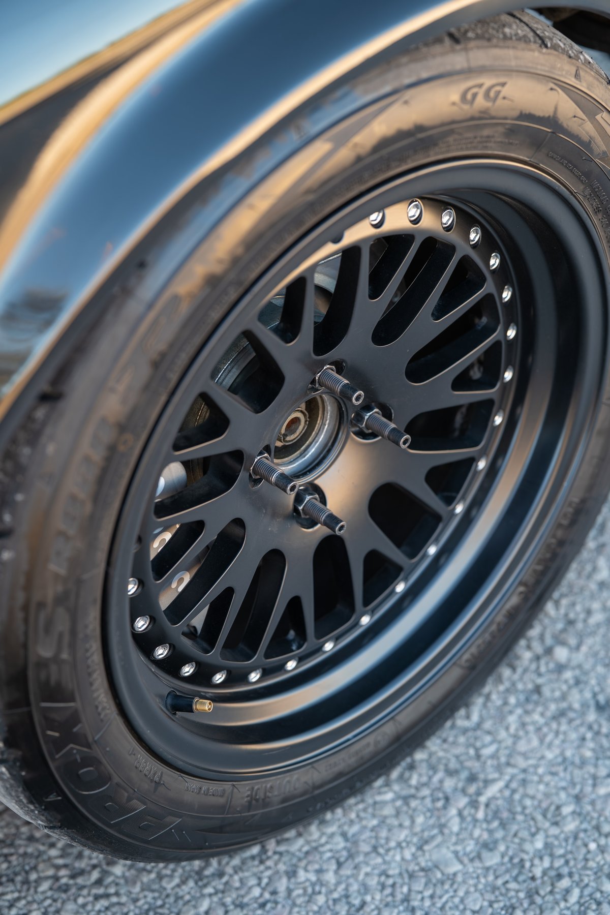 Black 1989 BMW 325is with black mesh alloy rims and performance tires.