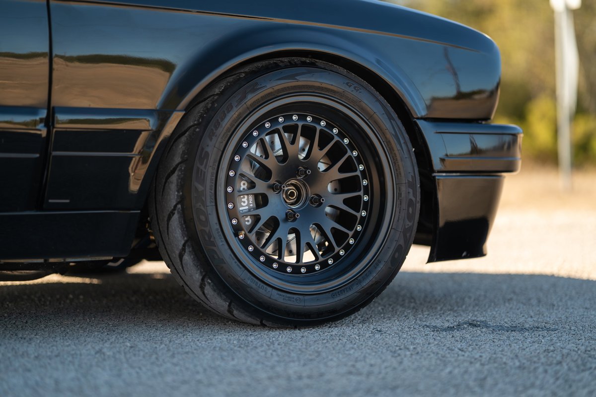 Black 1989 BMW 325is with black mesh rims and performance tires.