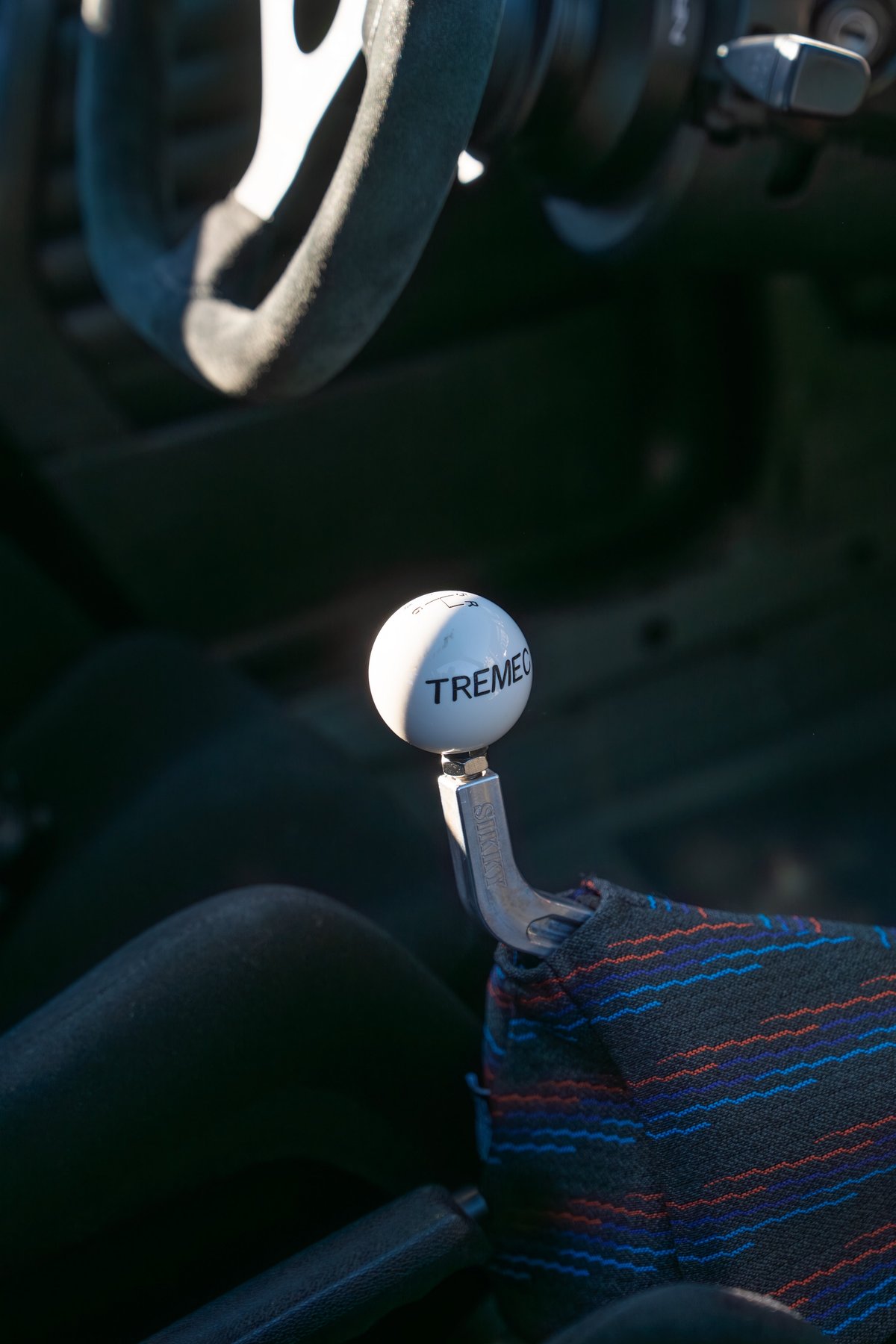 White TREMEC shifter ball and colorful patterned shift boot in a black 1989 BMW 325is.