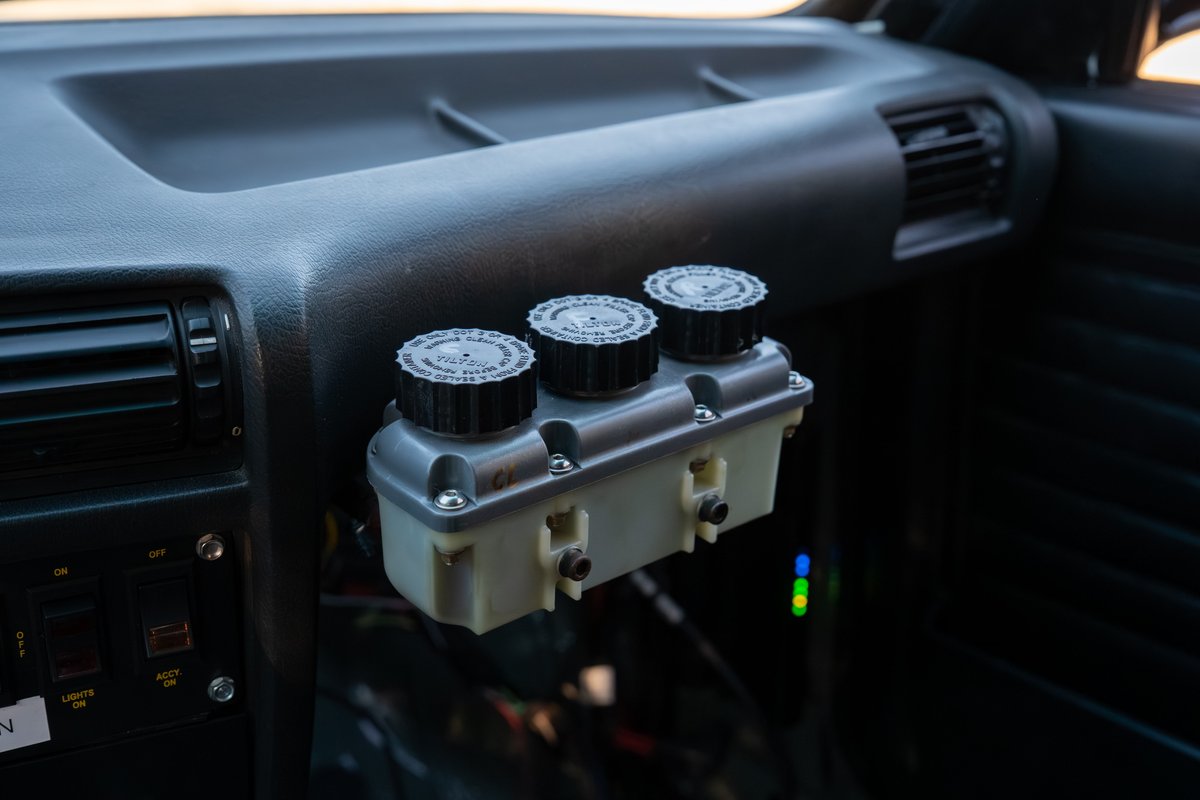 Black 1989 BMW 325is with triple brake fluid reservoirs mounted on the dash.