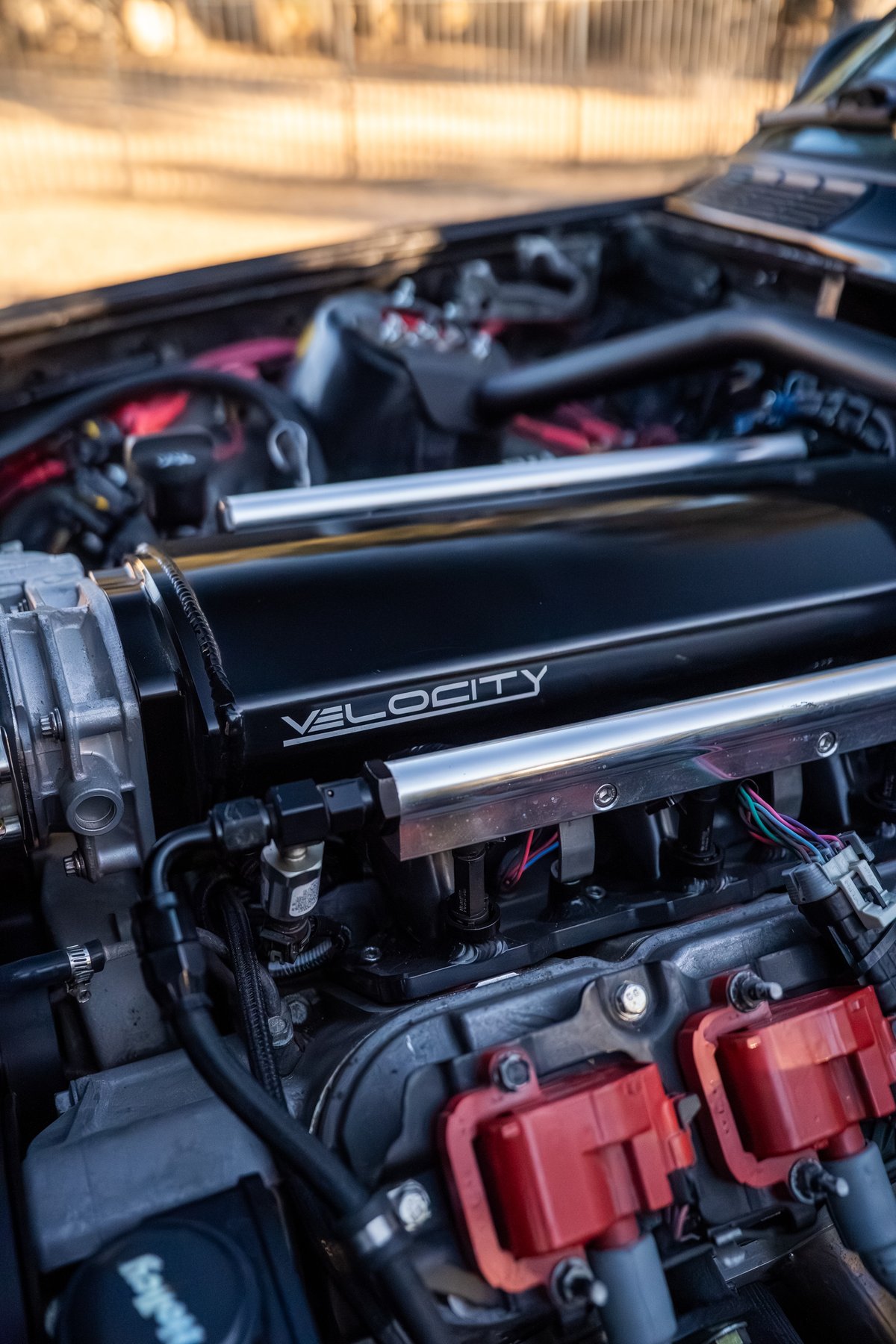 Black 1989 BMW 325is with a Velocity intake manifold and red ignition coils.