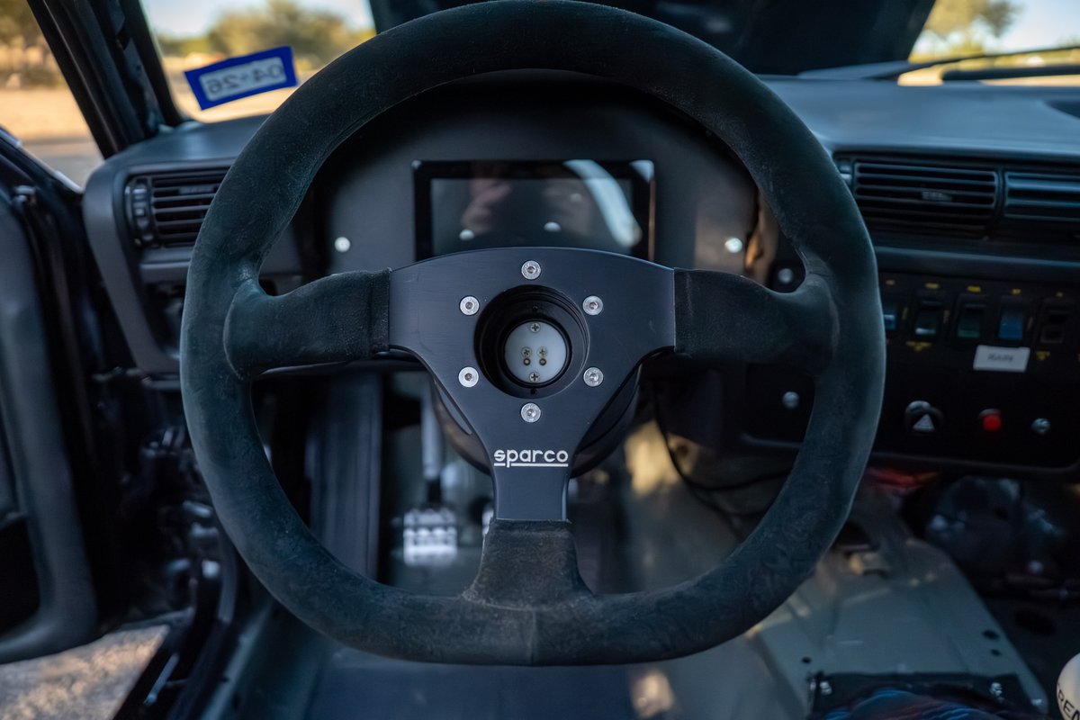 Black 1989 BMW 325is interior featuring a Sparco steering wheel and digital dash.