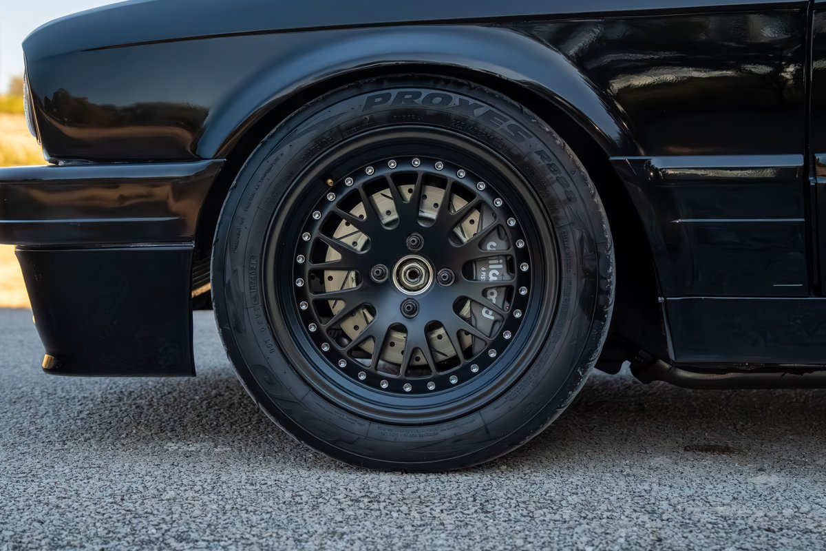 Black 1989 BMW 325is with custom black rims and drilled brake rotors.