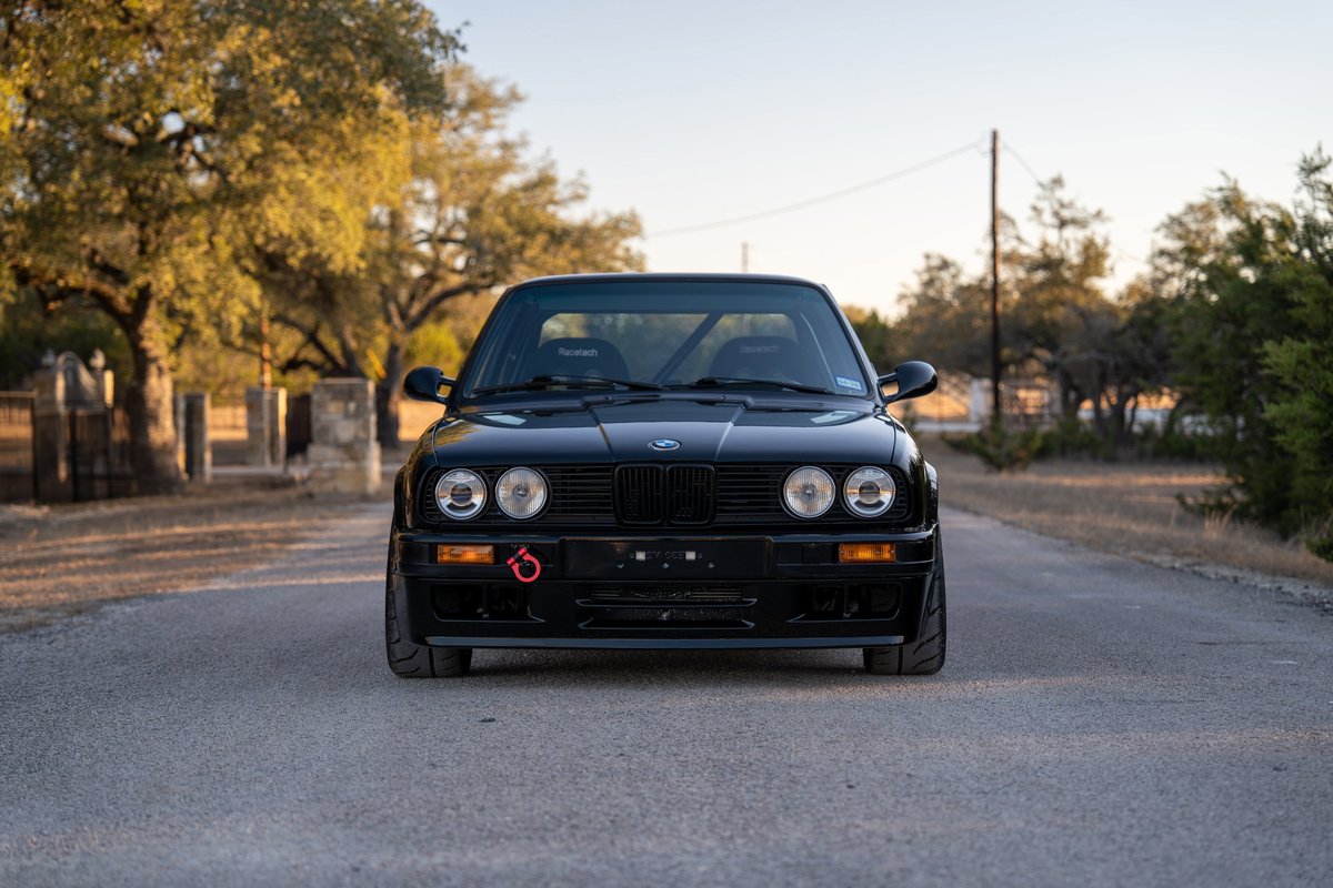 Front view of a black 1989 BMW 325is with racing seats and a tow hook.