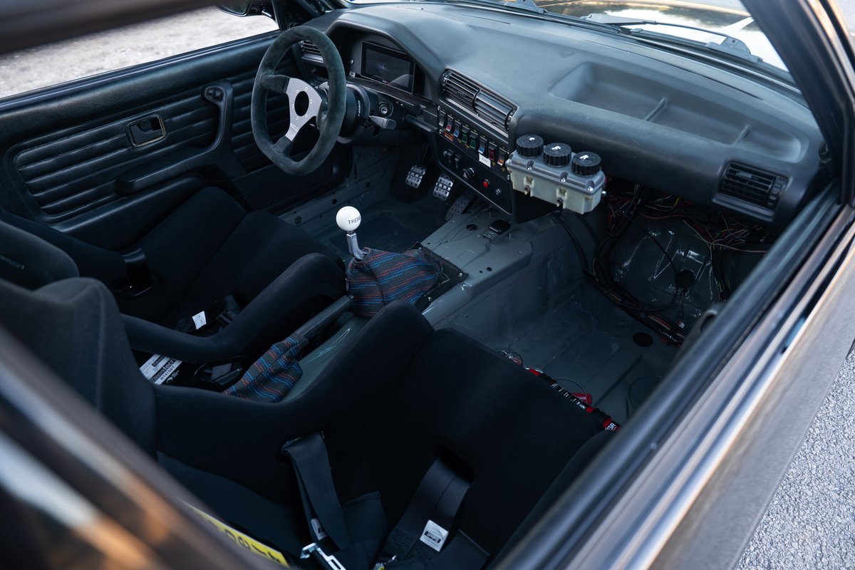 Black 1989 BMW 325is LS1 interior: racing seats, roll cage, aftermarket shifter.