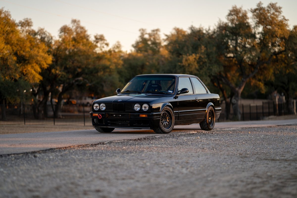 Black 1989 BMW 325is coupe with black rims, tow hook, and aftermarket trim.