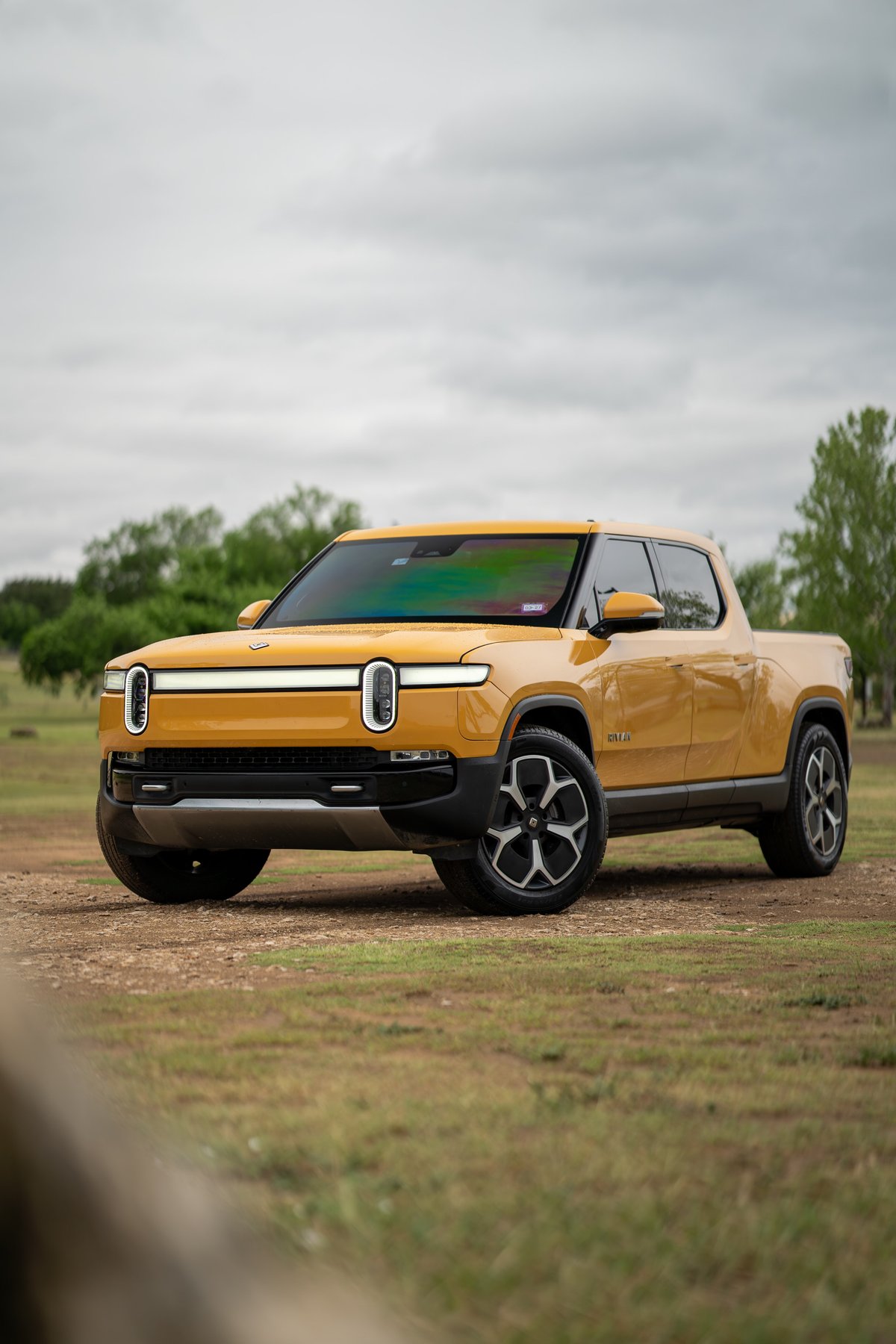 Yellow 2022 Rivian R1T pickup truck with unique rim design.