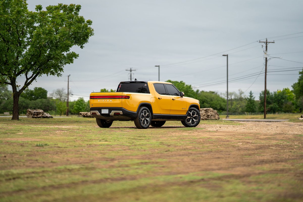 Yellow Rivian R1T electric truck with distinct rims and black trim.