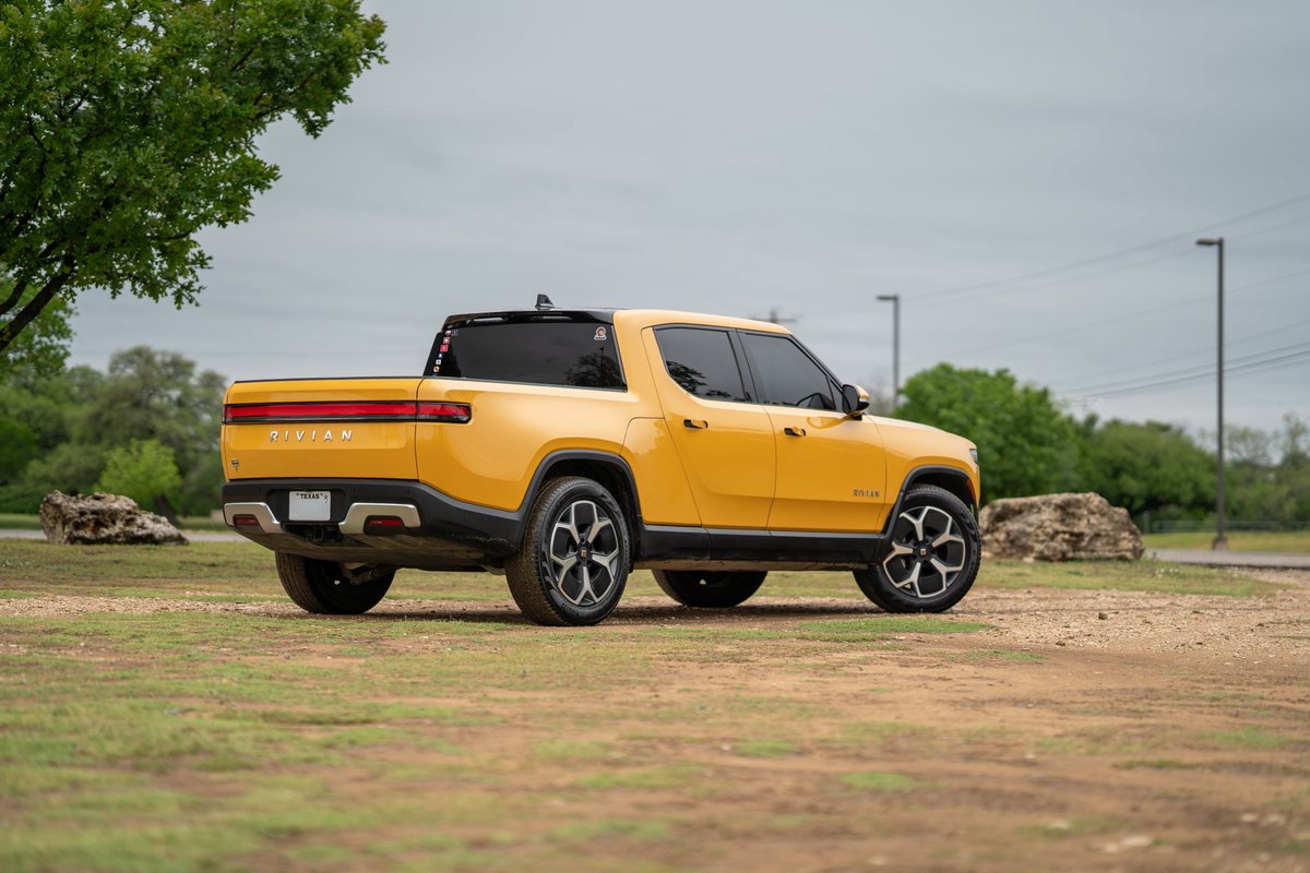 Yellow 2022 Rivian R1T electric truck with black trim and multi-spoke rims.