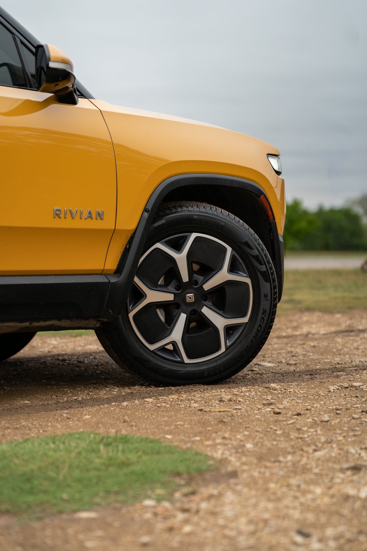 Yellow Rivian R1T front passenger wheel with multi-spoke rims and black trim.