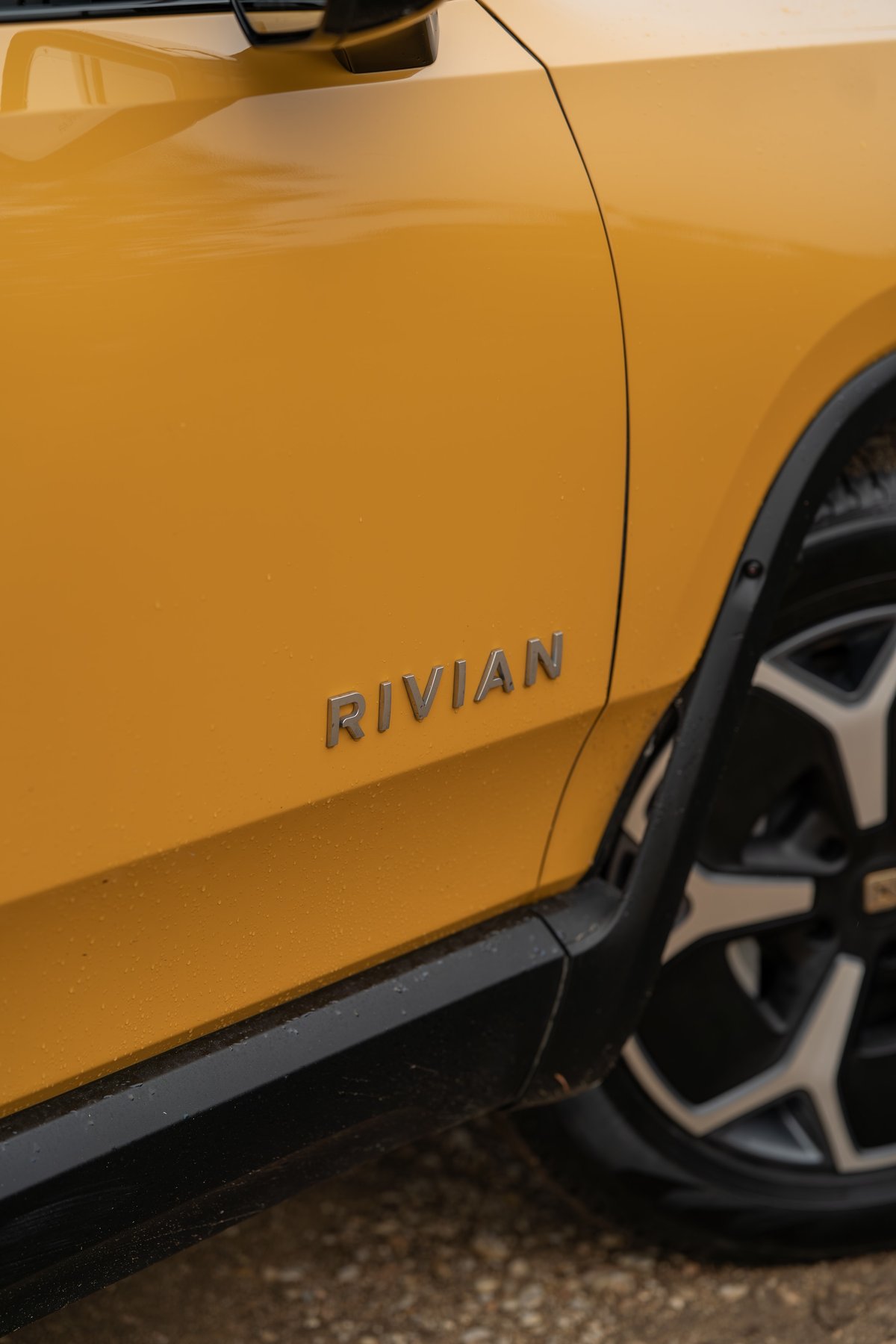 Yellow Rivian R1T with chrome badging and black trim.